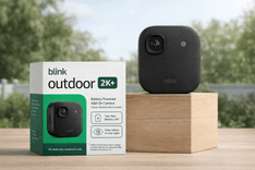 Blink Outdoor 2K+ wireless outdoor security camera with product box on wooden display